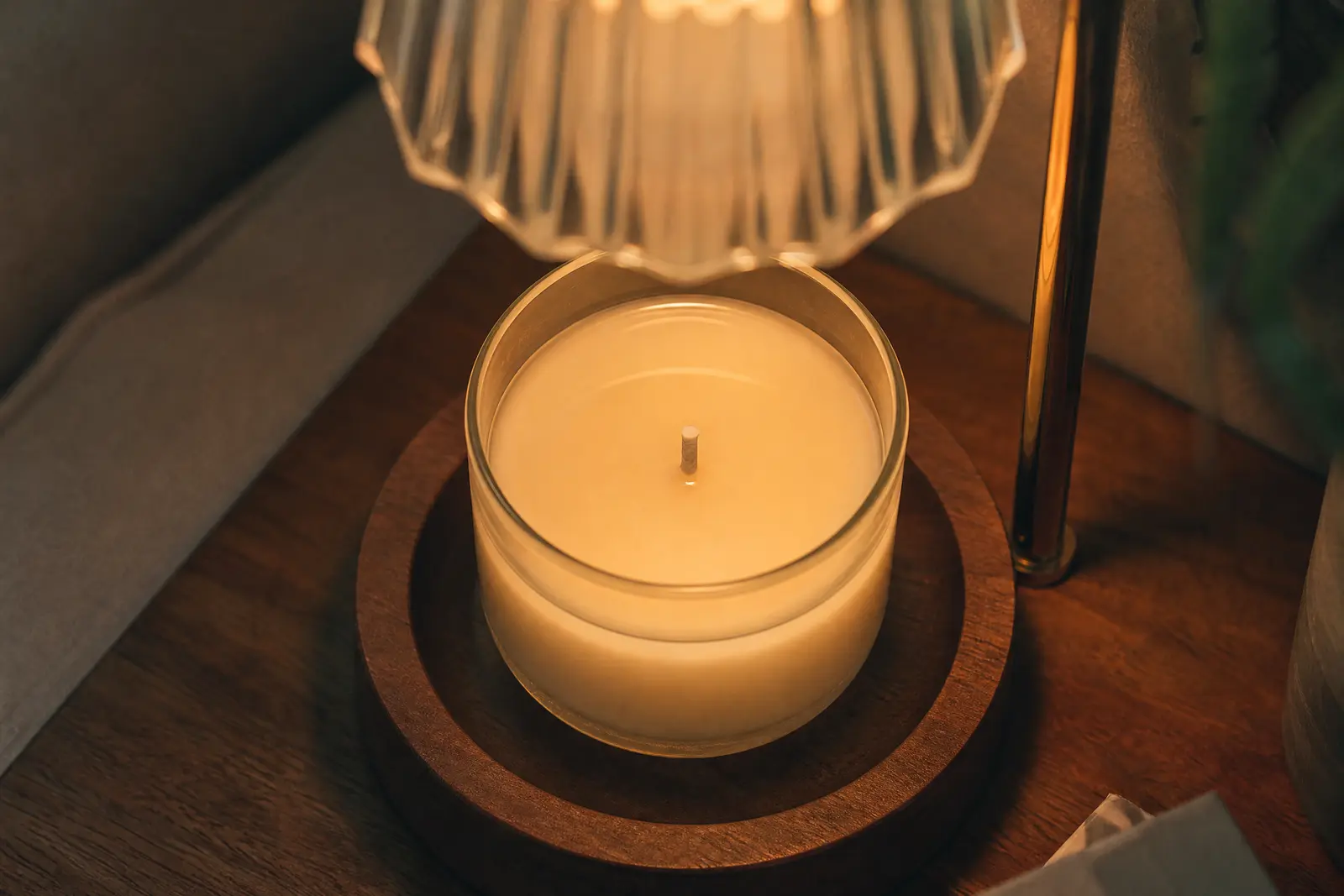 Jar candle under a candle warmer lamp with a smooth melt pool reaching the edges of the glass and no flame